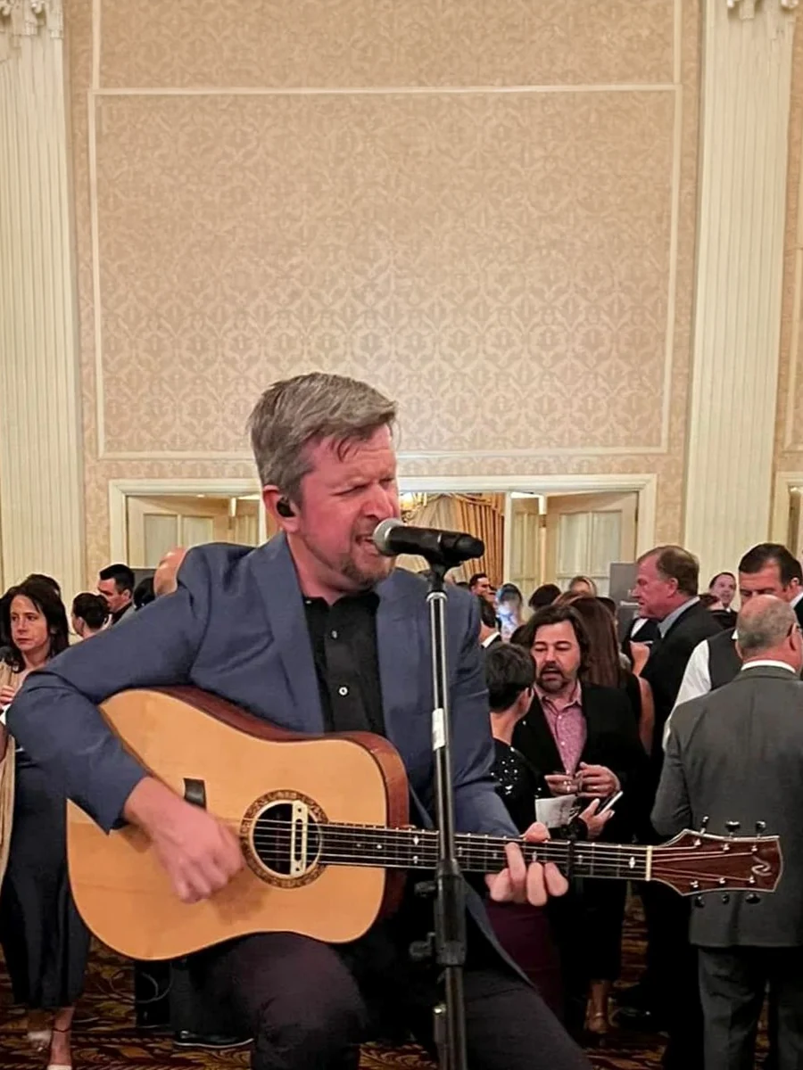 Phil Norby singing and playing acoustic guitar for event guests